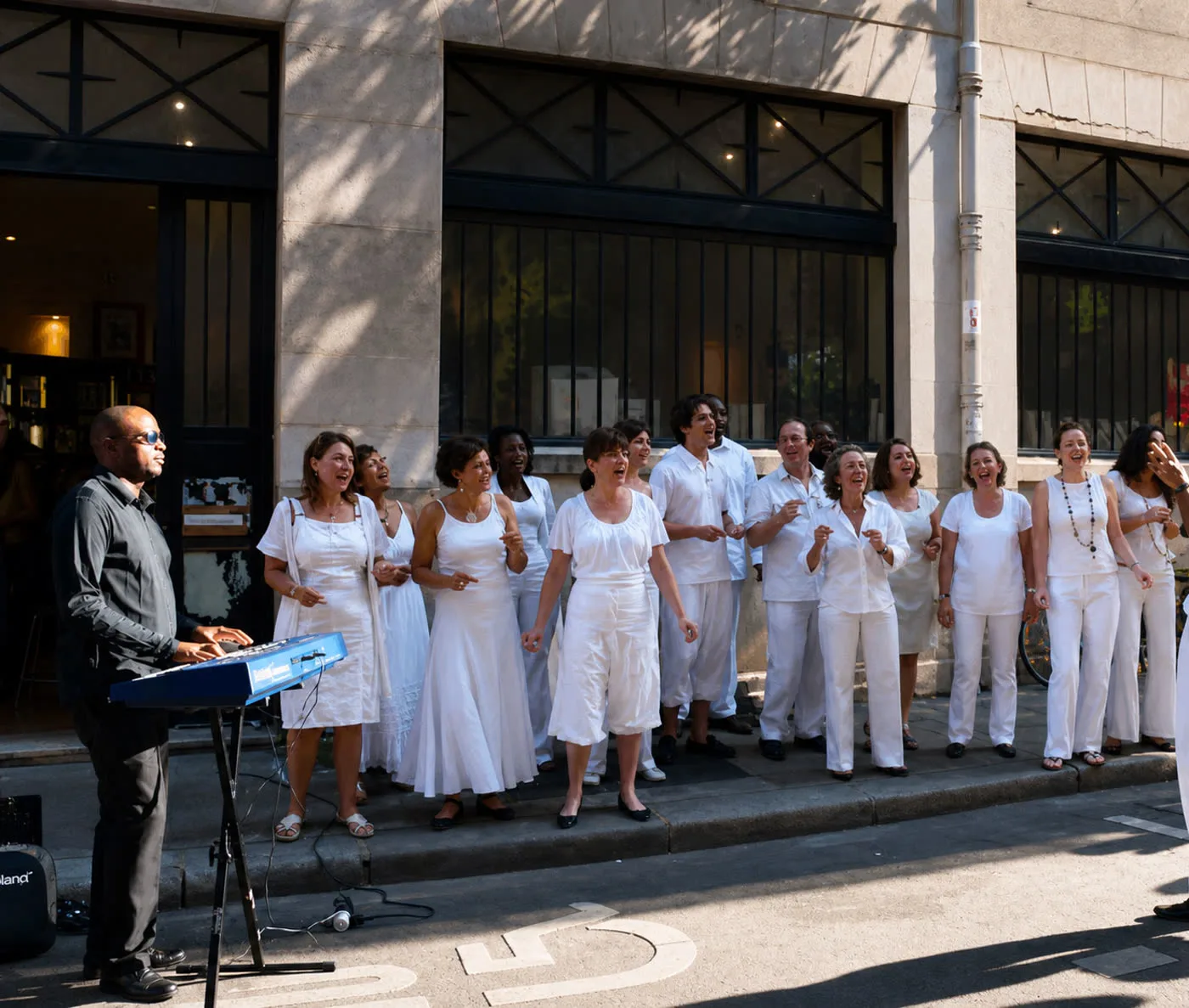 Chœur Max & Muses en tenue blanche chantant lors d'un événement en extérieur à Paris